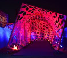 the entrance to an art gallery lit up in pink and blue lights with circles on it