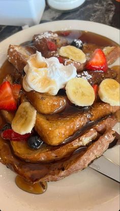 french toast topped with bananas, strawberries and syrup