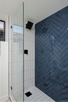 a bathroom with a walk in shower next to a blue tiled wall and white tile floor