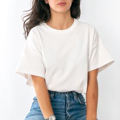 a woman wearing a white t - shirt and blue jeans is posing for the camera