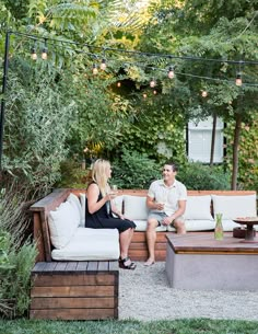 a man and woman sitting on top of a couch next to each other in a backyard