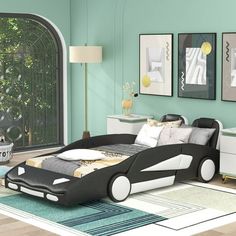 a modern bedroom with green walls and white furniture, including a black car shaped bed