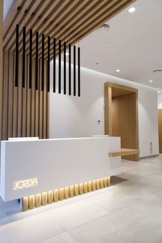 the front desk of a modern office with wood slats on the wall and floor