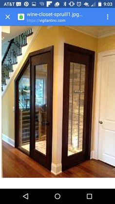 an empty room with two glass doors in the center and stairs leading up to the second floor