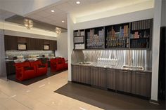 the interior of a modern restaurant with red chairs and bar area in the center,