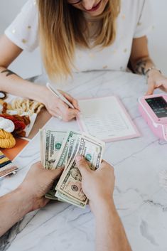 a person sitting at a table with money and a phone