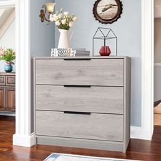 a gray dresser with flowers and books on top