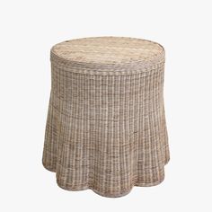 a wicker stool with a round top and pleated skirt on the bottom, against a white background