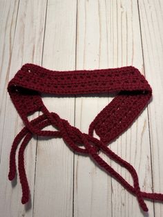 a red crocheted headband laying on top of a white wooden floor