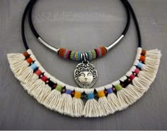 two necklaces with different colored beads and a face on one side, hanging from a black cord