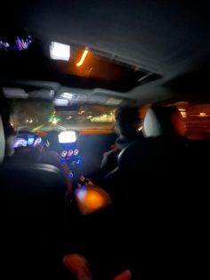 two people sitting in the back seat of a car at night with their lights on