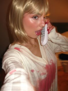 a woman holding a cell phone to her ear and making a funny face while talking on the phone