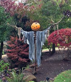 a scarecrow with a jack - o - lantern on it's head in a garden