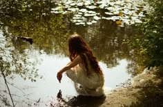 a woman sitting on the edge of a body of water