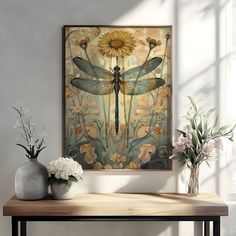 a table with vases and flowers on it in front of a large painting that has a dragonfly on it