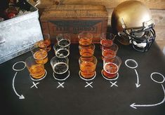 a football themed table with glasses and an old fashioned football helmet on the chalkboard