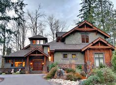 a large house in the woods with lots of trees and rocks on the front yard