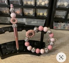 a pink and white beaded bracelet with flowers on it next to a black stand