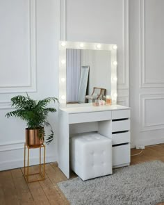 a white vanity with lights on it and a plant in the corner next to it