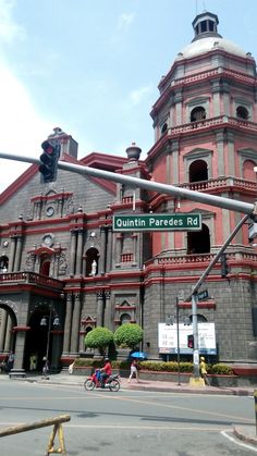 an old building with a traffic light in front of it and people riding bikes on the street