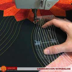 someone using a sewing machine to sew on an orange and black piece of fabric