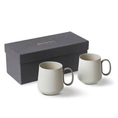 two coffee mugs sitting in front of a black box