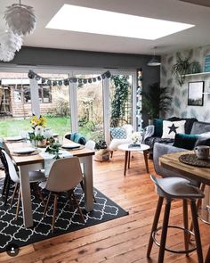 a living room filled with furniture and a wooden floor covered in lots of windows next to a patio