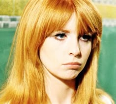 a woman with long red hair is looking at the camera while she's frowning