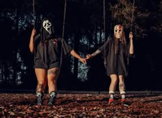 two people wearing masks holding hands on a swing