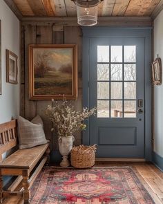 a room with a blue door and a rug on the floor next to a wooden bench