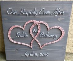 a wooden sign with two hearts and the words our happily ever after