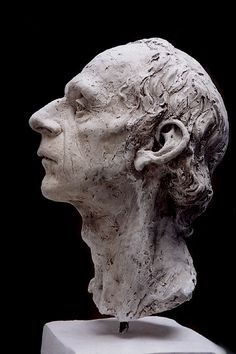 a white sculpture of a man's head with hair in the wind and his eyes closed