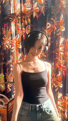 a woman wearing headphones standing in front of a curtain