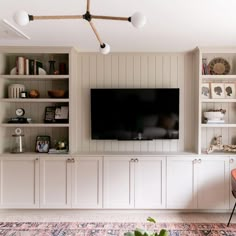 a living room with built in bookshelves and a flat screen tv mounted on the wall