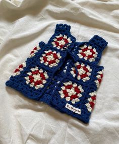 two crocheted blue and red sweaters laying on top of a white sheet