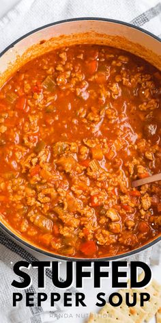 a pot full of stuffed pepper soup next to crackers on a white tablecloth