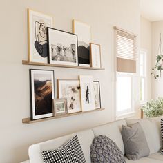 a white couch sitting in a living room next to a wall with pictures on it