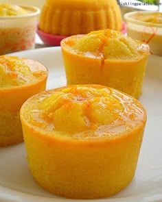 three orange cupcakes on a white plate next to other desserts in bowls