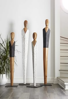 three wooden mannequins standing next to each other in front of a white wall