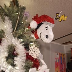 there is a christmas tree with decorations on it and a snoopy hat hanging from the top