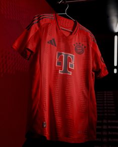 a soccer jersey hanging on a hanger in front of a red wall with lights