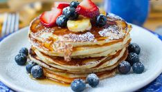 a stack of pancakes topped with fruit and powdered sugar