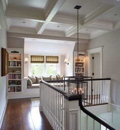 a living room filled with furniture and a book shelf next to a stair case in front of a window