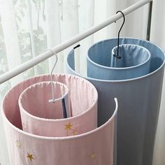 three round pink and blue storage bins with stars painted on them, hanging from hooks