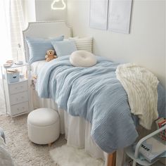 a small child's bedroom with blue and white bedding, teddy bear on the pillow