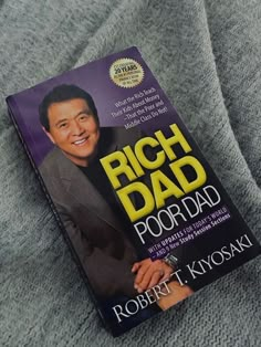 a book that is laying on top of a blanket with the title rich dad poor dad