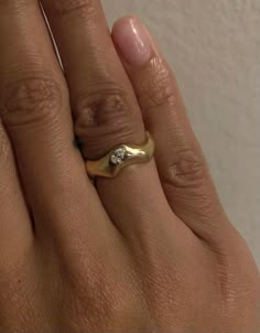 a woman's hand with a yellow gold ring and diamond on the middle finger