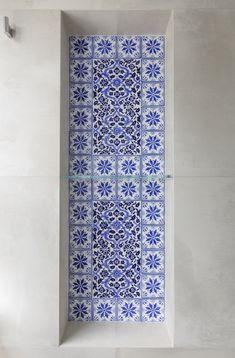 a blue and white tiled wall in the corner of a room with tile flooring