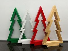 three wooden christmas trees sitting next to each other on a black counter top in front of a white wall