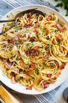 a plate of pasta with bacon, parmesan and parsley on the side